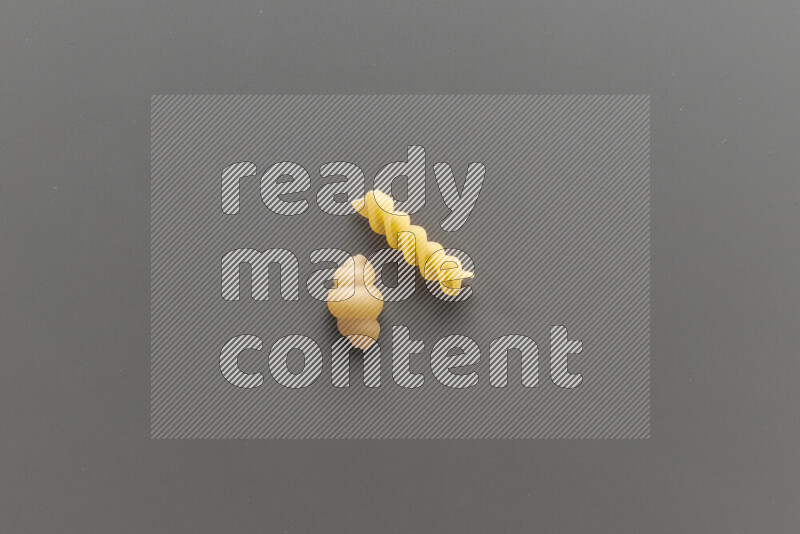 Snails pasta with other types of pasta on grey background