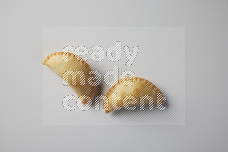 Two fried sambosa from a top angle on a white background