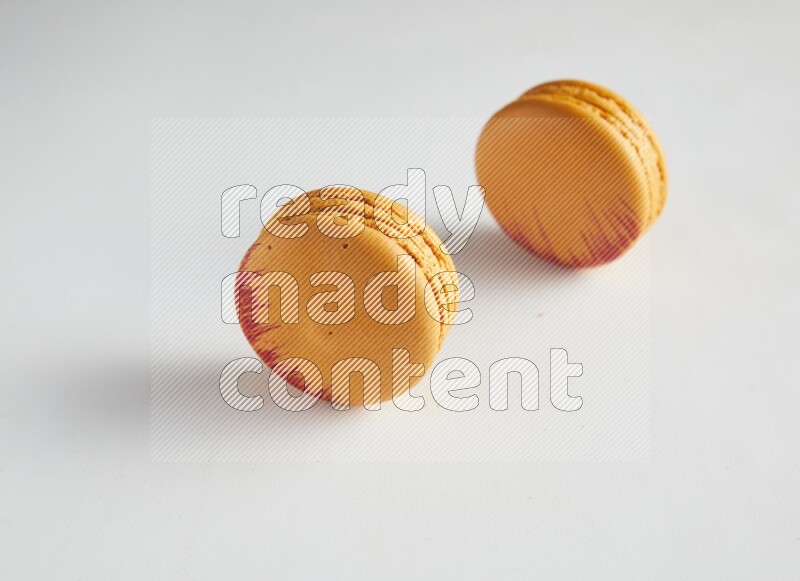 45º Shot of two orange Exotic macarons on white background