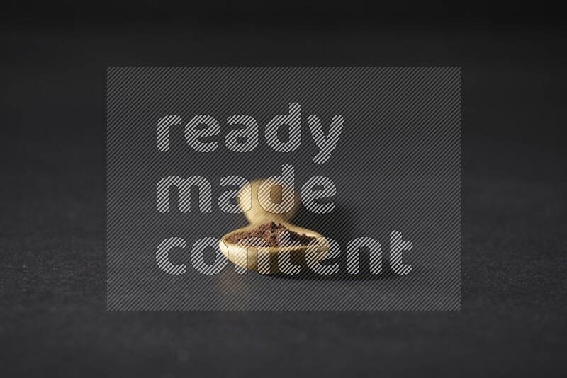 بودرة القرنفل في ملعقة خشبية علي خلفية سوداء