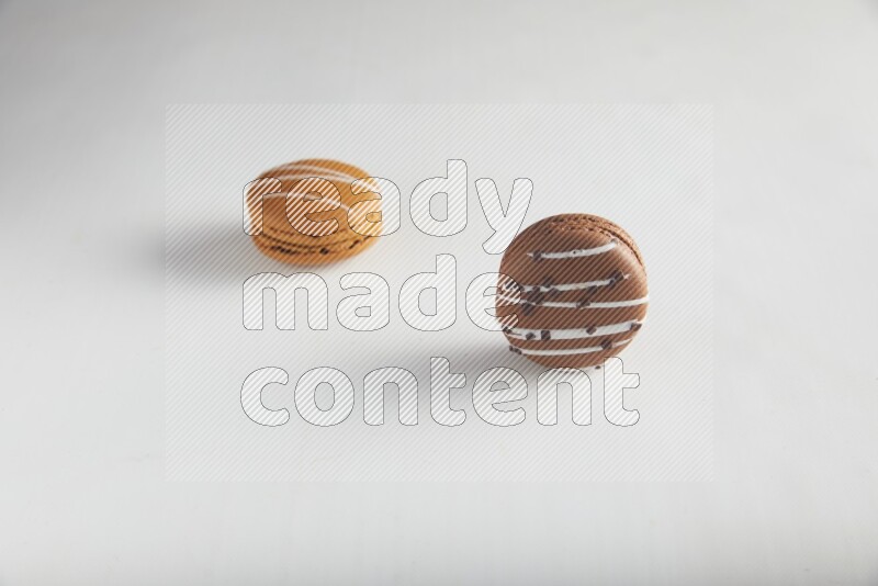 45º Shot of of two assorted Brown Irish Cream, and Brown white Chocolate Caramel macarons on white background