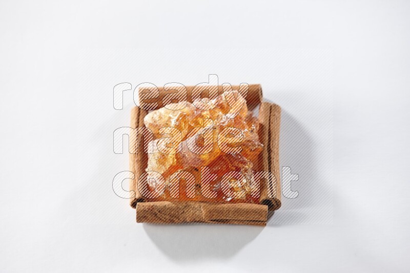 A single square of cinnamon sticks full of Arabic gum on white flooring