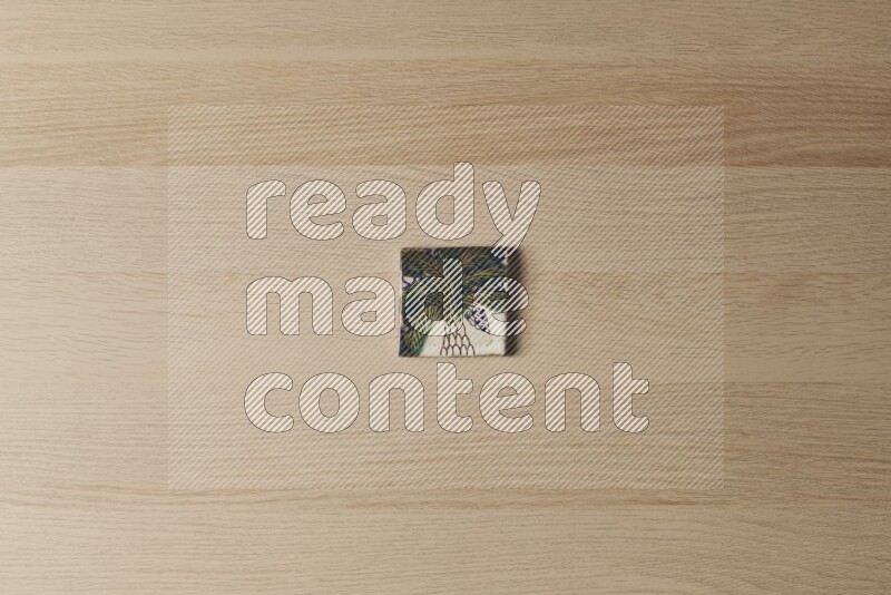 A decorative pottery coaster on light wooden background