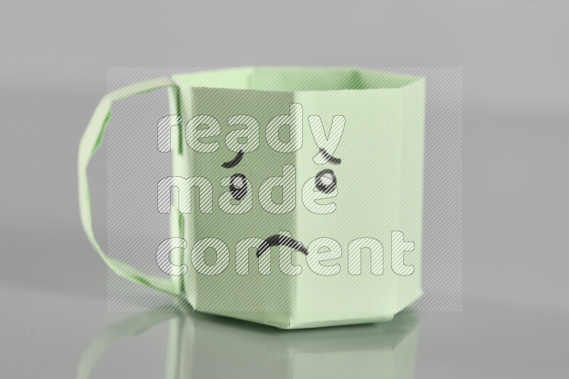 Origami cup on grey background