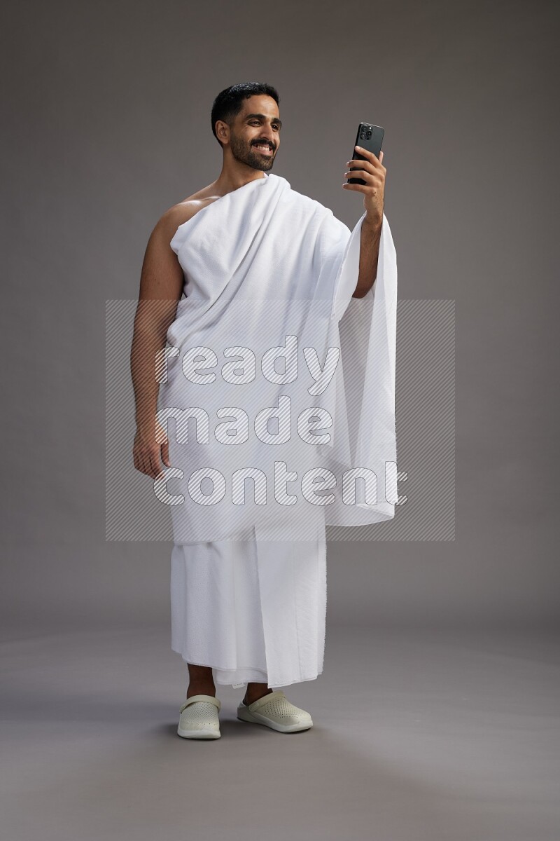 A man wearing Ehram Standing taking selfie on gray background