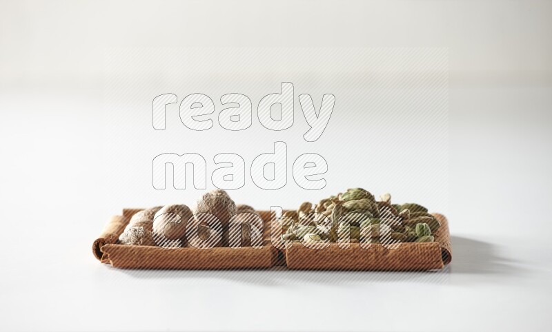 2 squares of cinnamon sticks full of cardamom and nutmegs on white flooring