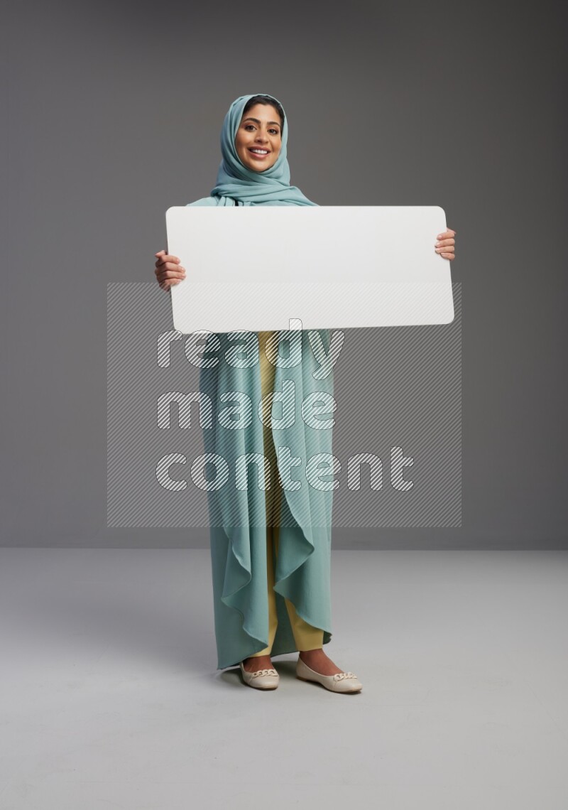 Saudi Woman wearing Abaya standing holding board on Gray background