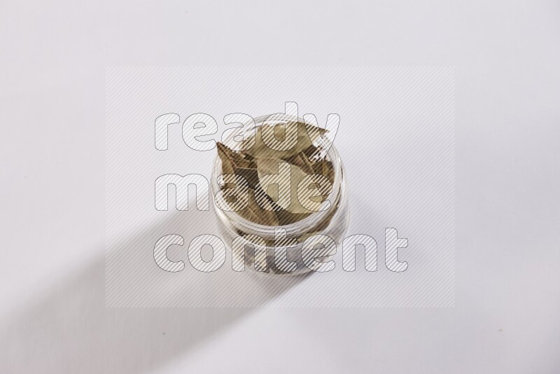 وعاء زجاجي ممتلئ بأوراق الغارعلي خلفية بيضاء