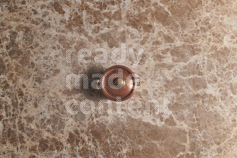A small copper pot on beige marble background