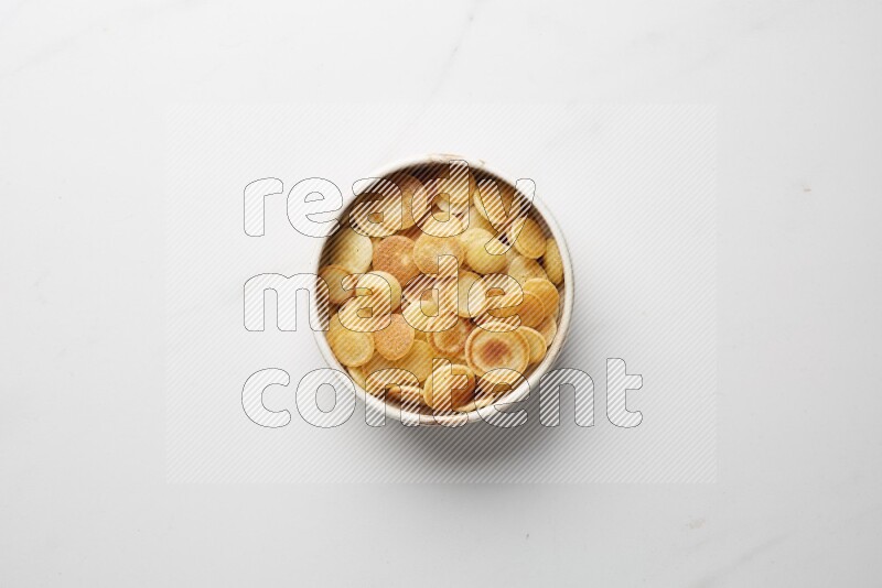 Top-view shot of plain cereal pancakes in a round bowl on white background