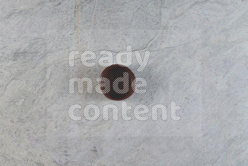 A brown pottery bowl on grey marble background