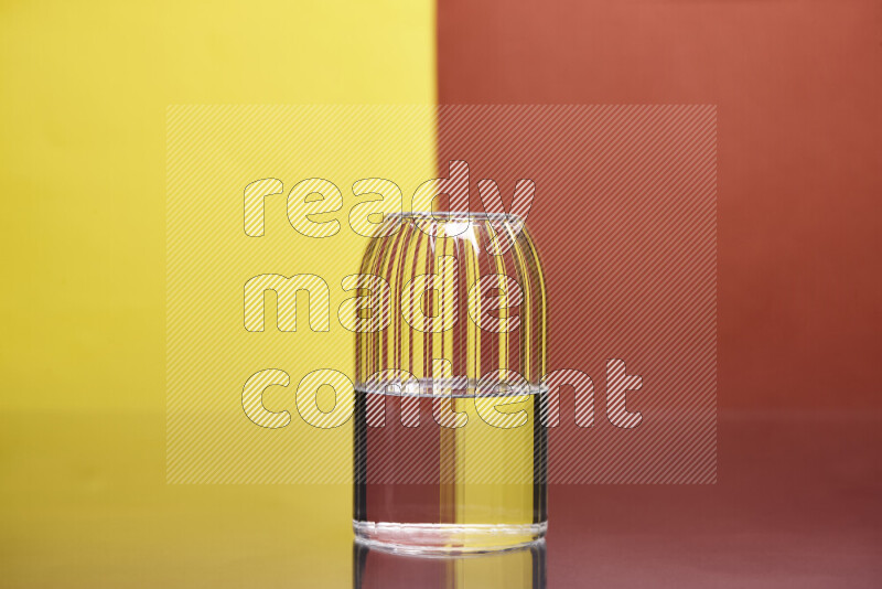 The image features a clear glassware filled with water, set against yellow and dark orange background