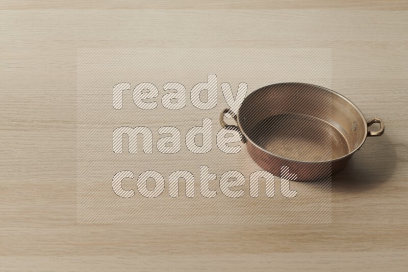 A small copper pan on light wooden background