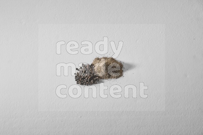 حبوب الفلفل الأسود والفلفل المطحون علي خلفية بيضاء