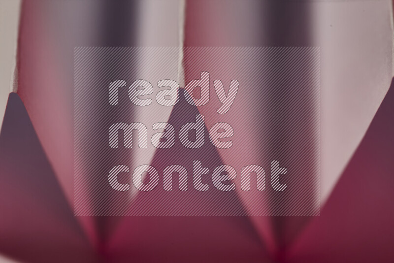 صورة مجردة مقربة تظهر طيات ورقية هندسية حادة بتدرجات اللون الأبيض و الأحمر