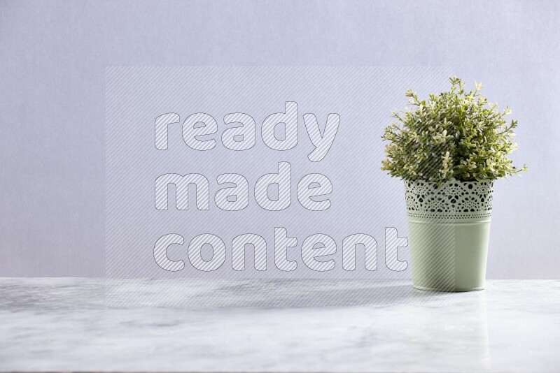 Artificial plant in green decorative pot on grey marble background