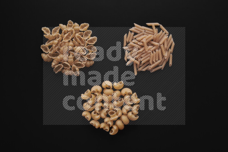 Different pasta types in bunches on black background
