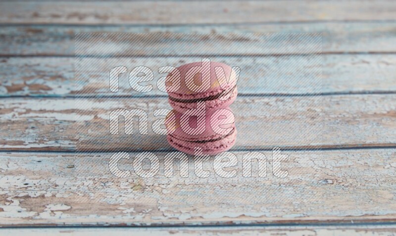 45º Shot of two Purple Strawberry macarons on light blue wooden background