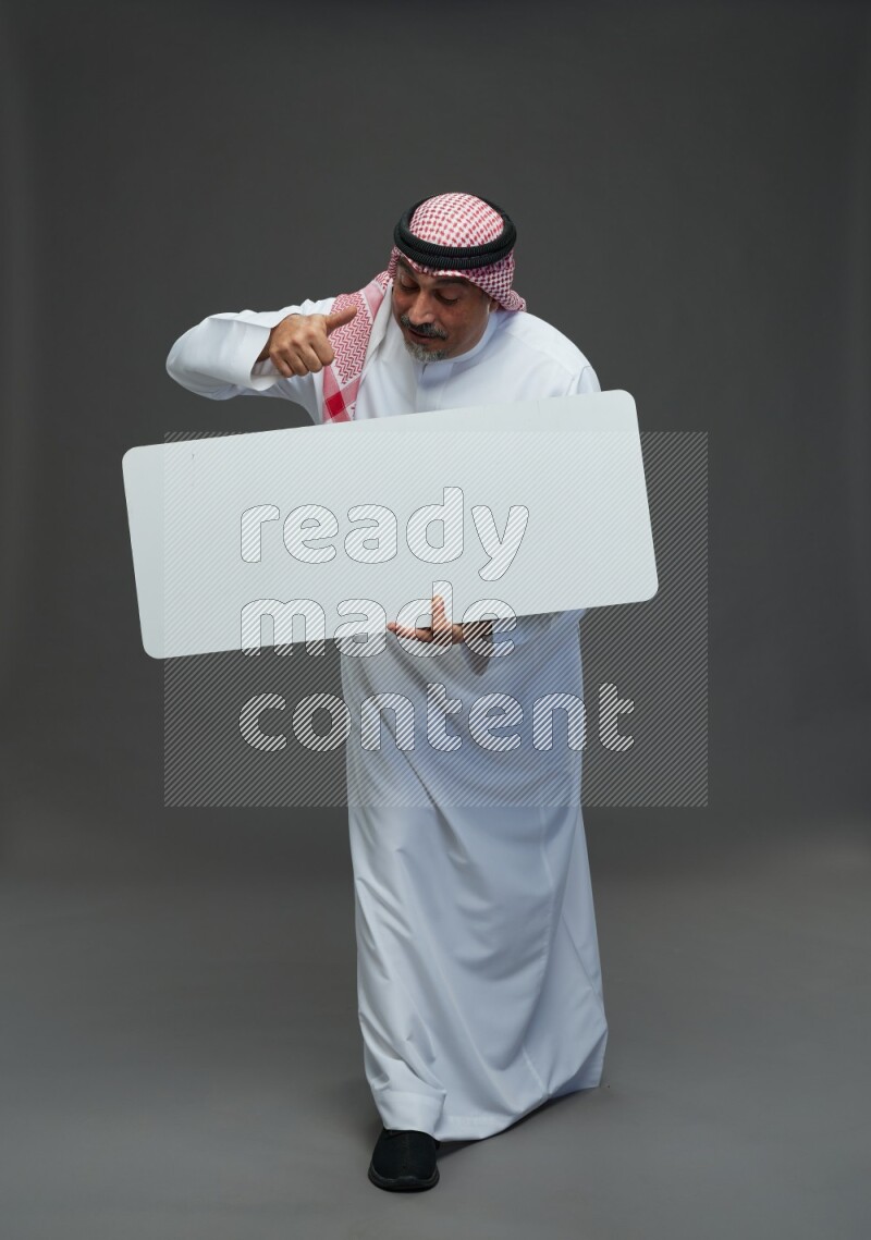 Saudi man with shomag Standing holding social media sing on gray background