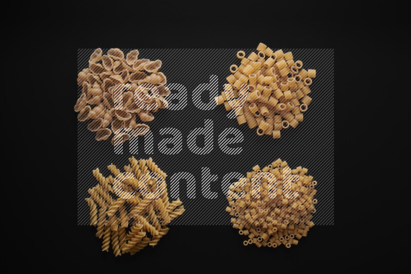 Different pasta types in bunches on black background