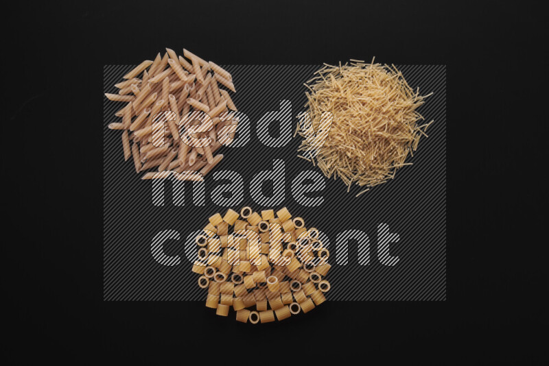 Different pasta types in bunches on black background