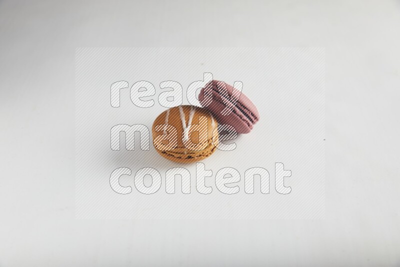 45º Shot of of two assorted Brown Irish Cream, and Red Poppy Flower macarons on white background