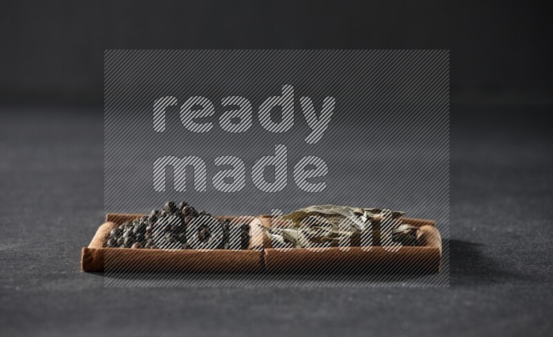 2 squares of cinnamon sticks full of black peppers and bay laurel leaves on black flooring
