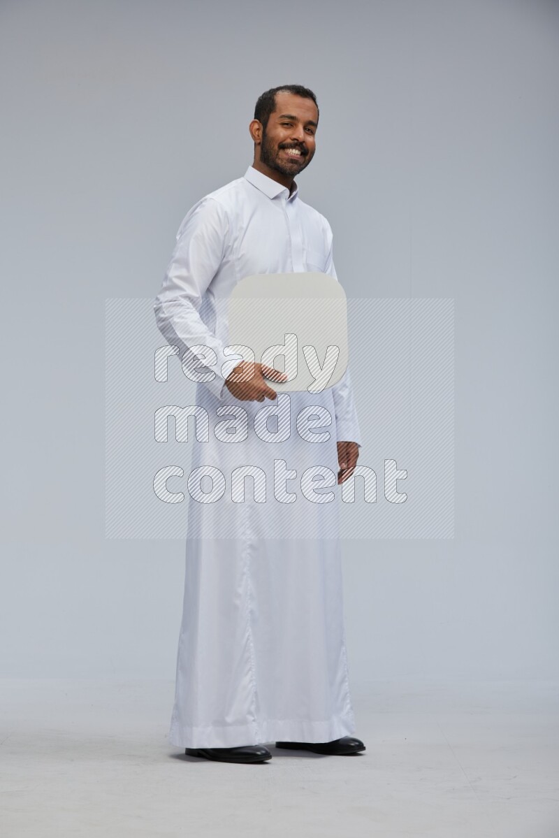 Saudi man wearing Thob standing holding social media sign on Gray background