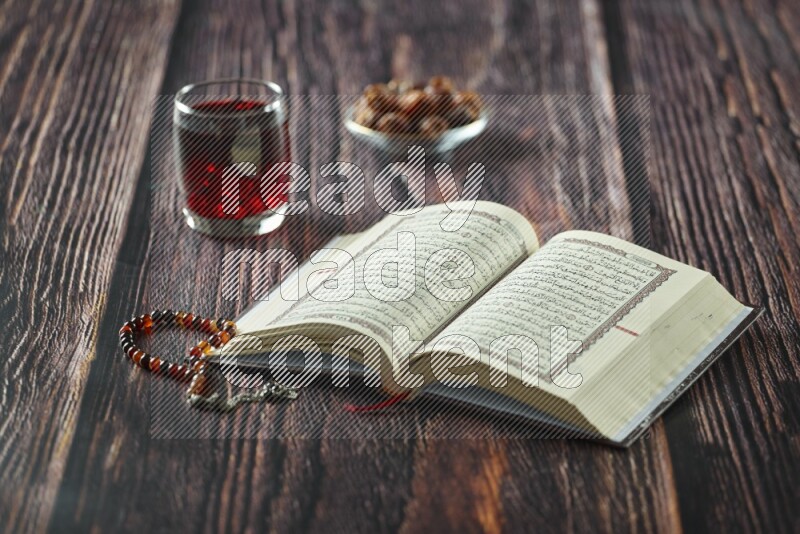 Quran with dates, prayer beads and different drinks all placed on wooden background