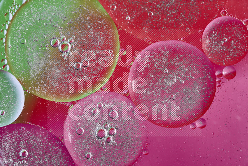 Close-ups of abstract oil bubbles on water surface in shades of pink, green and red