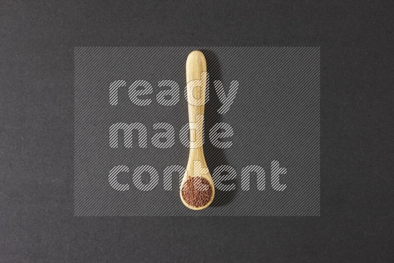 ملعقة خشبية ممتلئة ببذور حب الرشاد علي خلفية سوداء