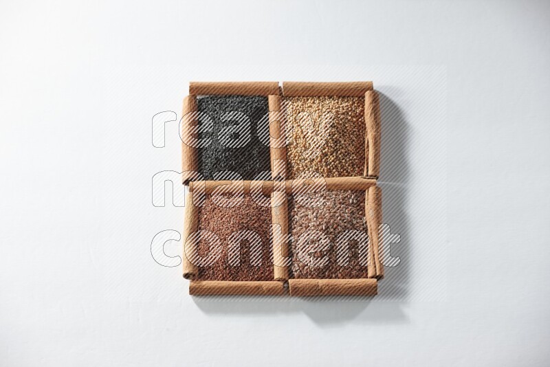 4 squares of cinnamon sticks full of black seeds, mustard seeds, flaxseeds and garden cress on white flooring