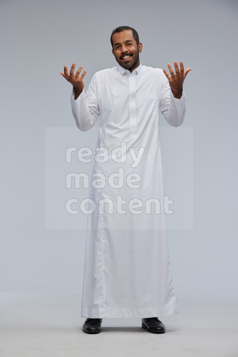 Saudi man Wearing Thob standing interacting with the camera on Gray background