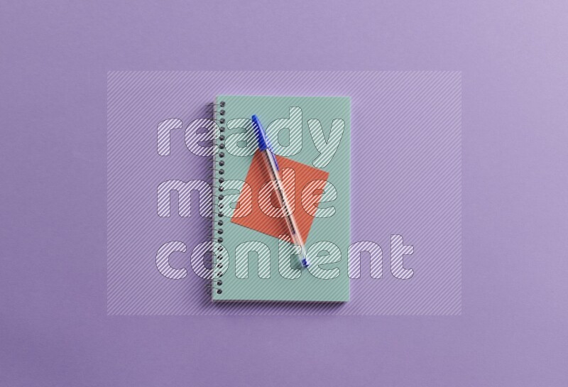 A blue notebook with school supplies on purple background