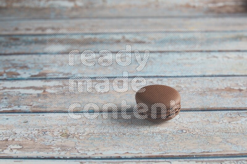 45º Shot of Brown Dark Chocolate macaron on light blue wooden background