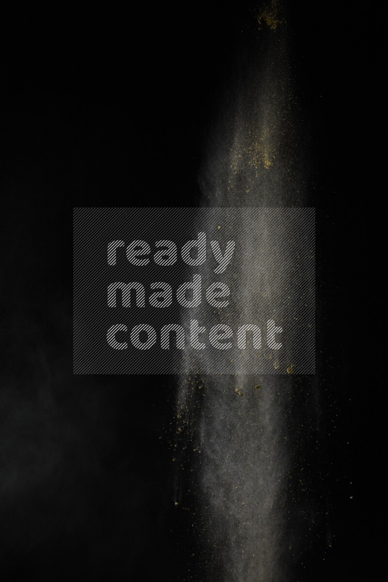 A side view of yellow powder explosion on black background