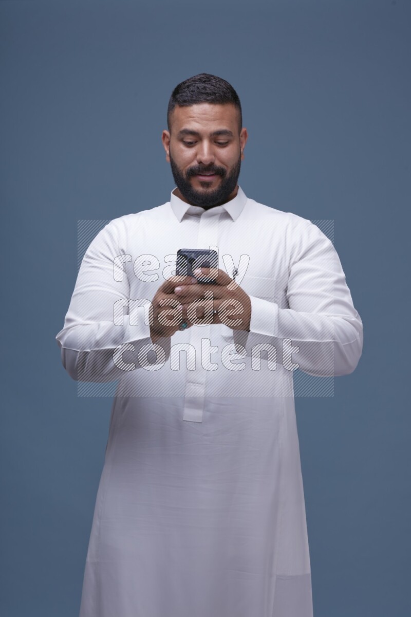 A man Texting on Blue Background wearing Saudi Thob
