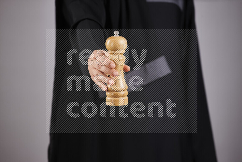 A woman in black abaya holding different wooden essentials in different positions