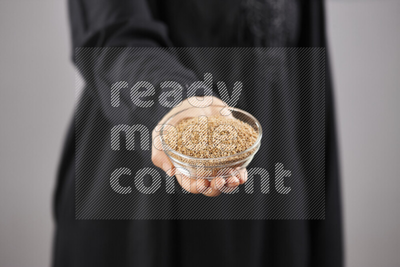Woman in abaya holding different kinds of spices in different positions