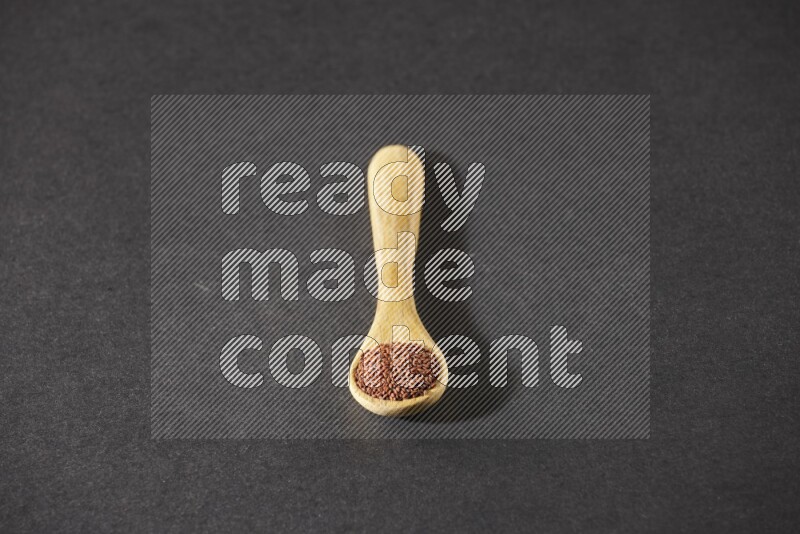 ملعقة خشبية ممتلئة ببذور حب الرشاد علي خلفية سوداء