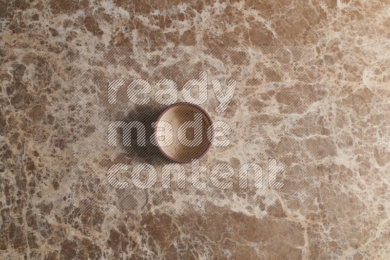 A beige pottery bowl on beige marble background