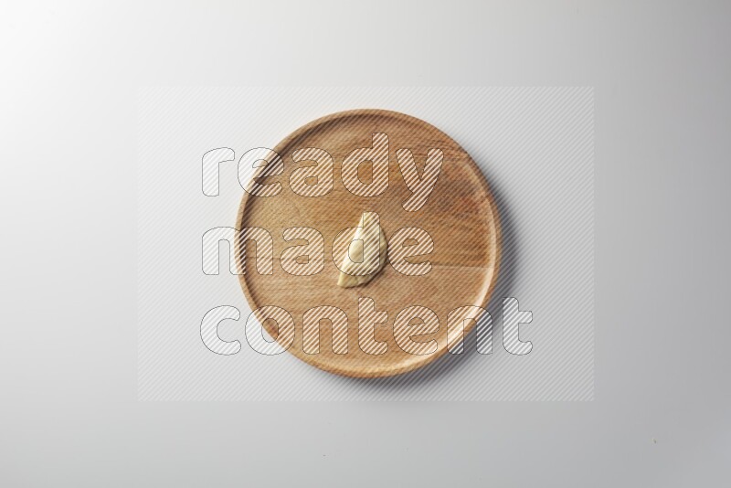 A single Sambosa on a wooden round plate on a white background