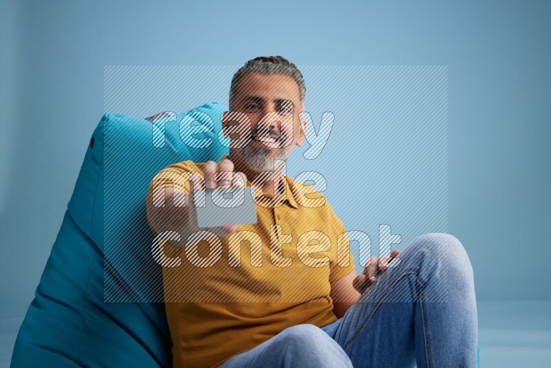 A man sitting on a blue beanbag and holding ATM card