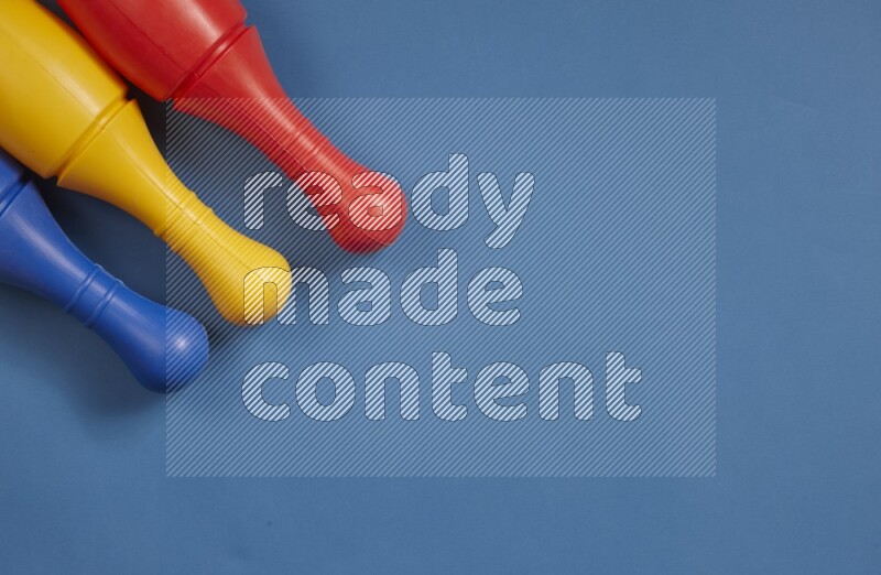 Multicolored plastic bowling pins on different colored backgrounds background (kids toys)