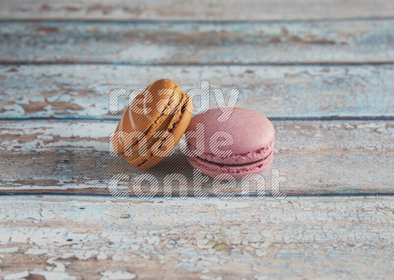 45º Shot of of two assorted Brown Irish Cream, and Purple Strawberry macarons  on light blue background