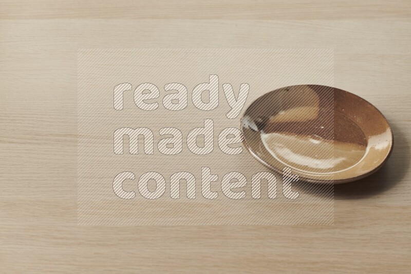 A multicolored pottery plate on light wooden background