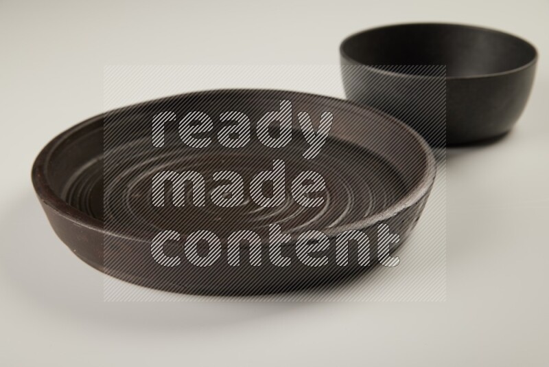 black pottery plate and black bowls on white background