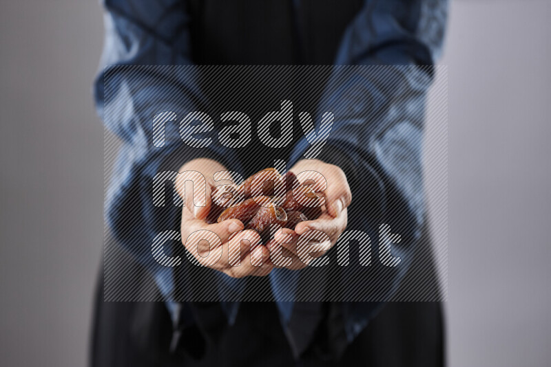 Woman in abaya holding dates in different positions