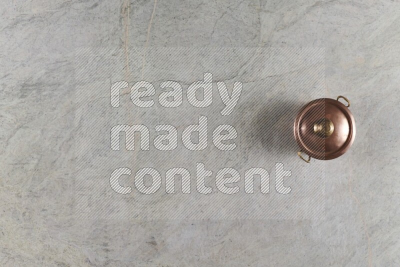 A small copper pot on grey marble background