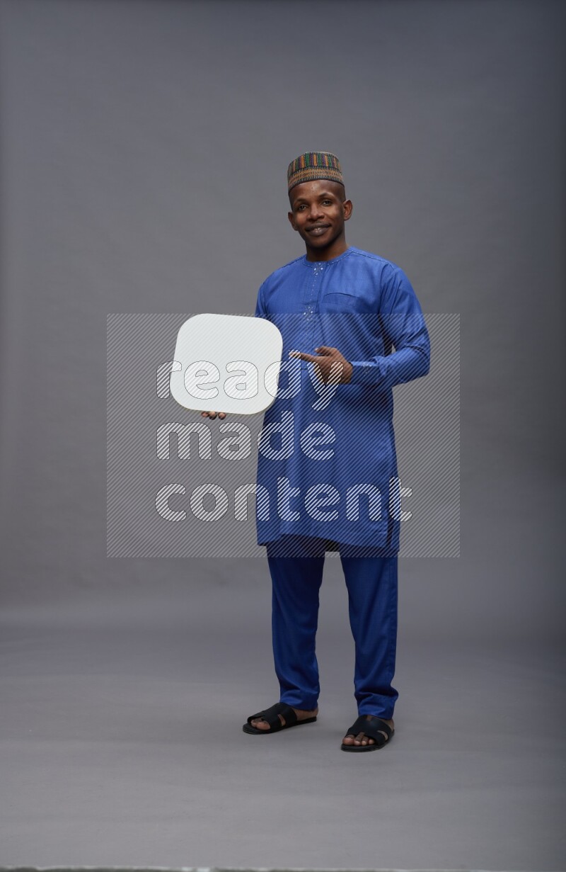 Man wearing Nigerian outfit standing holding social media sign on gray background